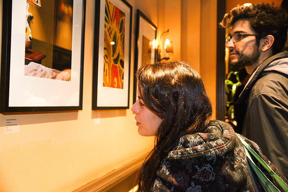 Guests look at the photographs displayed during the "Room 704" exhibit on Thursday, March 27, 2014. Photo by Ekevara Kitpowsing/The Guardsman