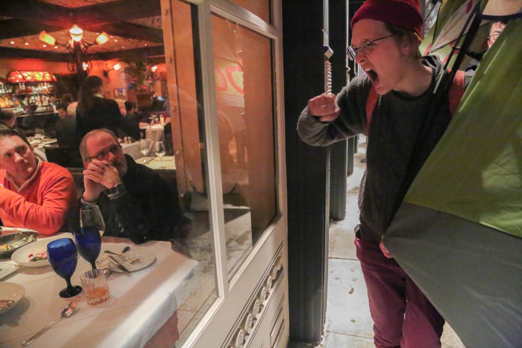 Activist catch the attention of diners by banging on the window as they mach around Super Bowl City. Protesters chanted: "Hey Ed Lee, No Penalty for for Poverty!" (Photos by Gabriella Angotti-Jones)