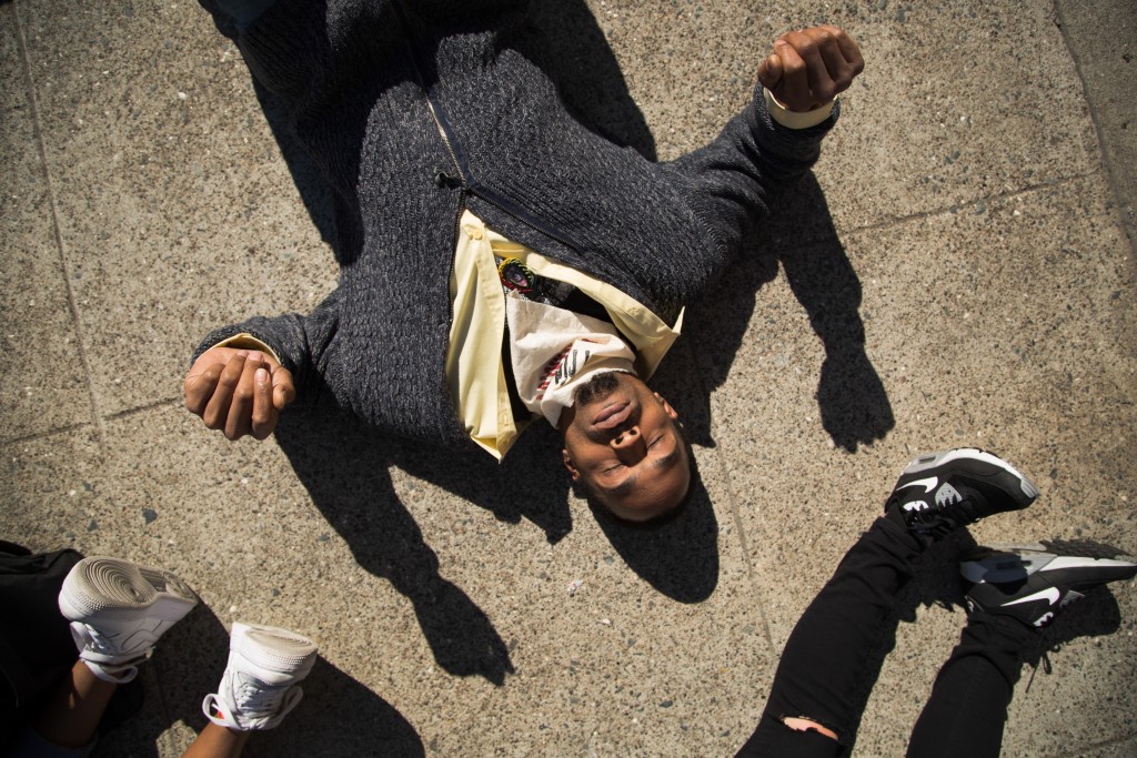 Hip-hop artist Sellassie of the Justice for Mario Woods Coalition partici- pates in a “die-in” outside City Hall to demand justice for Alex Nieto. (Photo by Gabriella Angotti-Jones / The Guardsman)