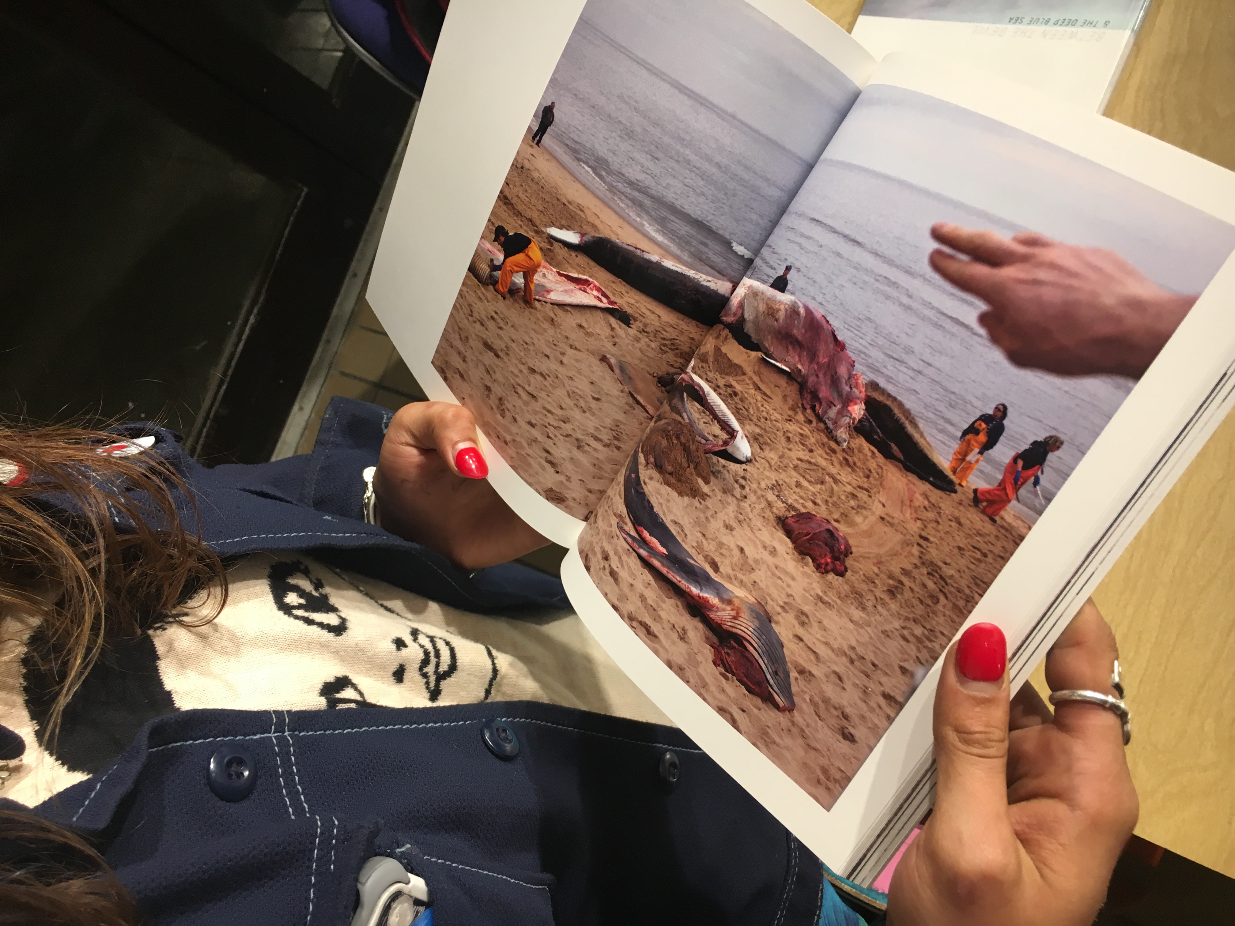 CCSF photography student Rebecca Diablo stares at a whale carcass photo in Preston Gannaway’s visual essay book, “Between the Devil and the Deep Blue Sea” on September 6, 2017. (Photo by Laurie Maemura) 