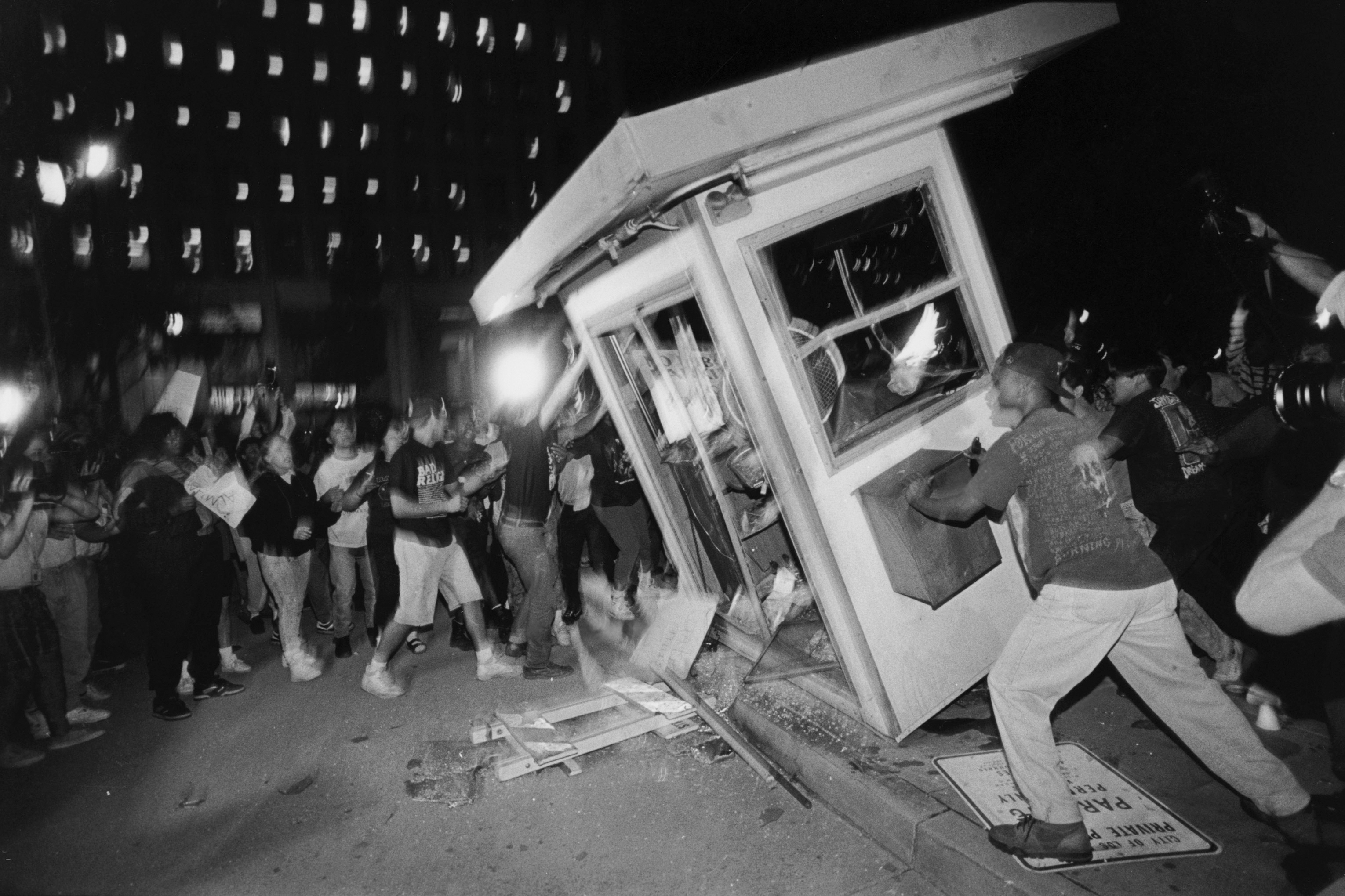 Rioters overturn a parking attendant booth at the LAPD Parker Center in downtown Los Angeles during the 1992 riots that swept the city for days after three of four police officers accused of the 1991 beating of Rodney King were cleared of all charges. The fourth officer was charged with use of excessive force. (Photo by Ted Soqui/Corbis via Getty Images)