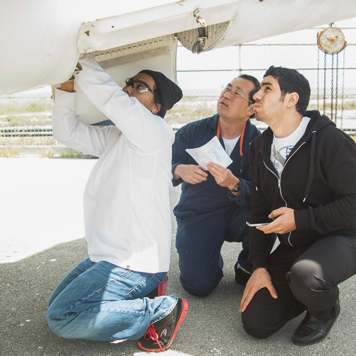 (L-R) Students Aries Gerald Pangan, 21, Peter Yuthrayard, 43, and Kerols Shafik, 25, inspect the Sabreliner T-39 air conditioning bay.