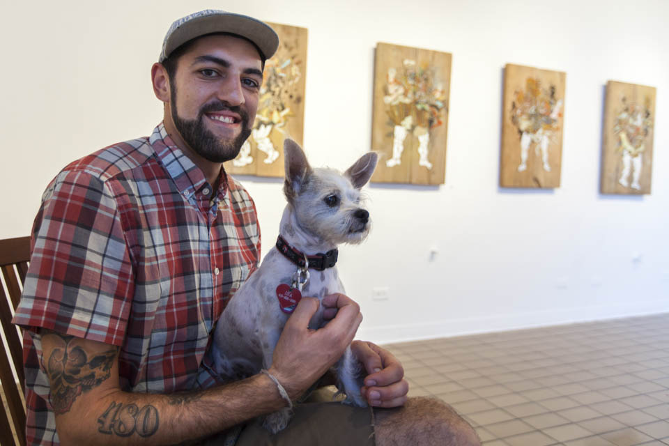 David Polka sits with his dog during the opening reception of his art exhibition at the City College Art Gallery, Thursday, Oct. 2. (Photo by Nathaniel Y. Downes)