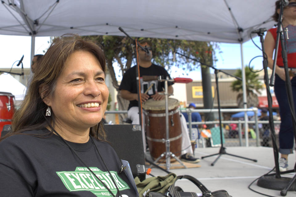 A City College alumni and the music coordinator of 12th Annual Excelsior Art & Music Festival, Rosario Cervantes, stands in front of the music stage while Puerto Rican music band ‘La Mixta Criolla’ performs at the Sunday Streets Festival in The Excelsior, San Francisco on Sunday, Sept. 28, 2014. Each year Sunday Streets collaborates with the Excelsior Art & Music Festival to bring fun activities to the community. (Photo by Ekevara Kitpowsong)