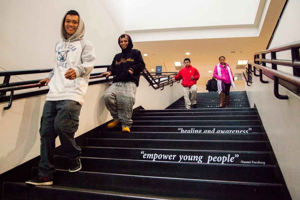 Students descend the stairs of the Rosenberg Library where excerpts from Project SURVIVE's testimonials are displayed. (Photo by Ekevara Kitpowsong)
