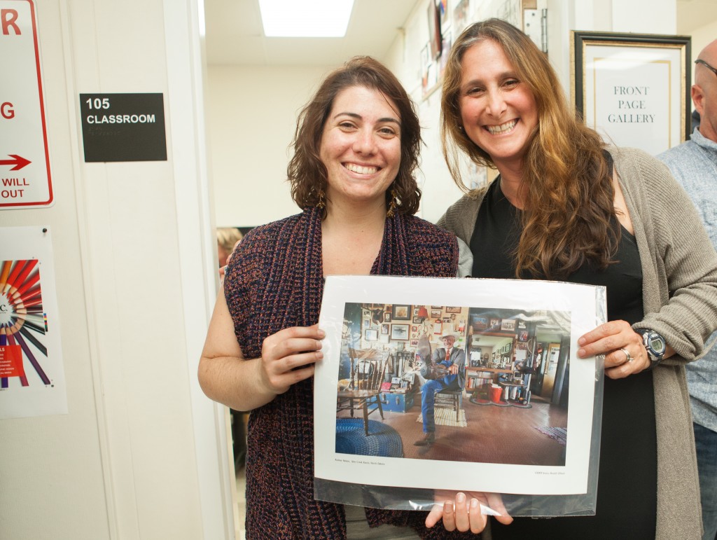 (L-R) Sara Bloomberg, former editor-in-chief of The Guardsman, won a photograph by Jessica Lifland from the raffle during the opening reception for “Faces of Hope” at Front Page Gallery on Thursday, Sept. 17, 2015. (Photo by Ekevara Kitpowsong/The Guardsman)