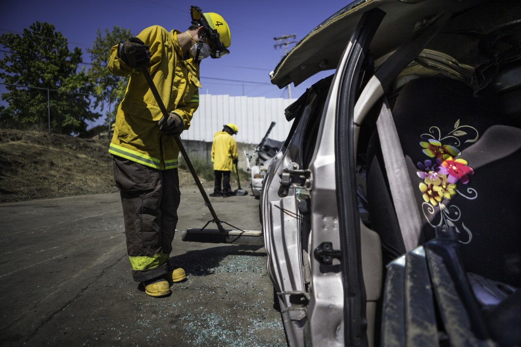 Fire cadet William Scott Cowell from City College’s Fire Fighter One Academy’s Class 15 cleans up the yard after practicing auto extrication techniques at San Jose Pick and Pull on Saturday, April 18, 2015. (Photo by Nathaniel Y. Downes/The Guardsman)