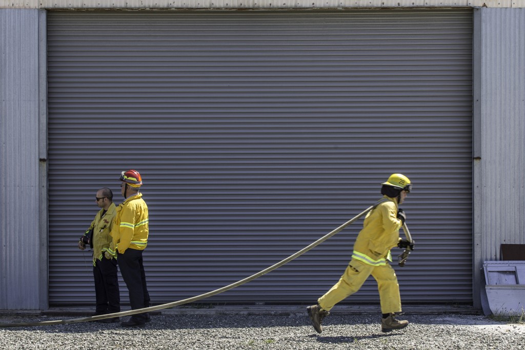 A fire cadet from City College’s Fire Fighter One Academy’s Class 15 runs a hose during a wlidland training drill while instructors look on at Cal Fire’s North Division Fire Station in San Mateo on Saturday, March 28, 2015. (Photo by Nathaniel Y. Downes/The Guardsman) 