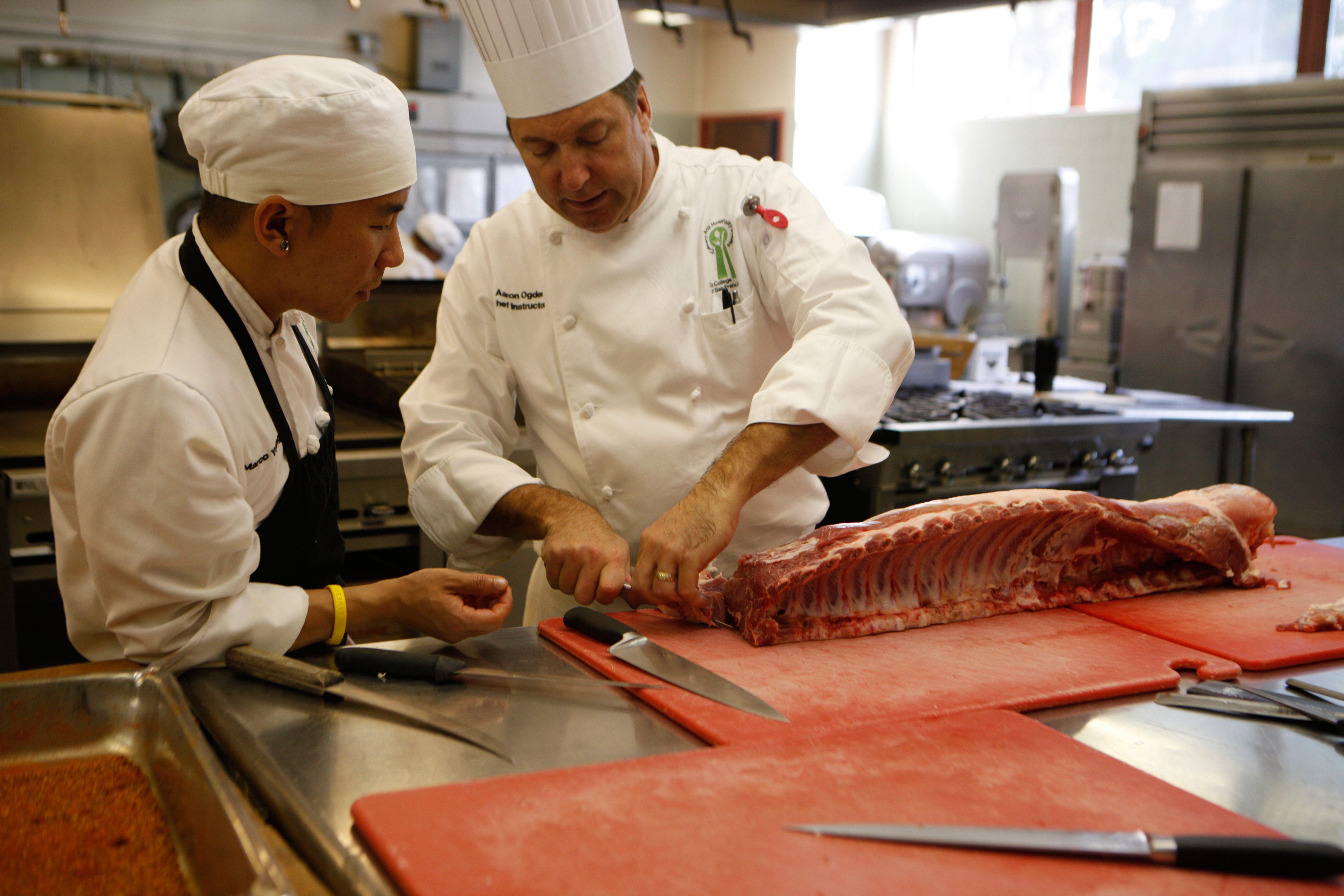 Chef Aaron Ogden, right, shows second-semester culinary student Marco Young how to cut beef sections. (Photo by Franchon Smith/ The Guardsman)