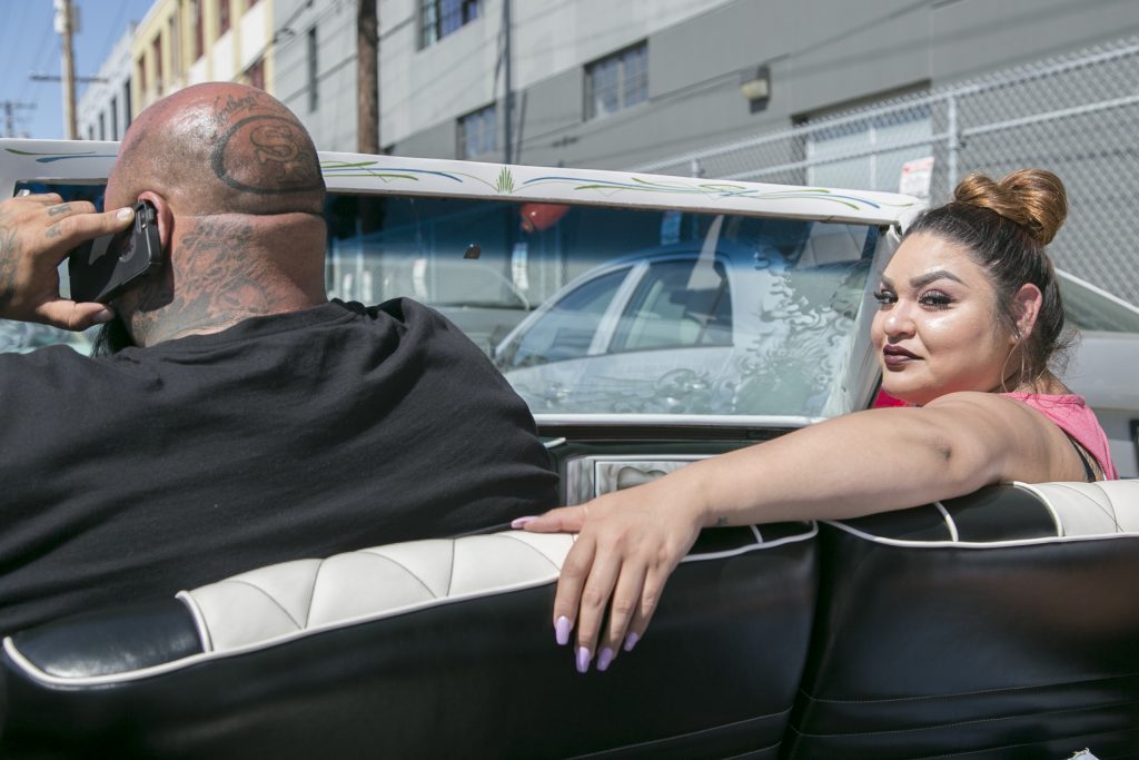 Karla Alarco glances behind her from the passenger seat of a lowrider car outside the car show. (Photo by Gabriella Angotti-Jones).