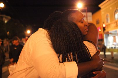 Mustafah Grenne (right), Tiara J (middle) and April Martin (right) share a hug after their performance at the intersection of 22nd and Mission St on Nov. 3, 2016