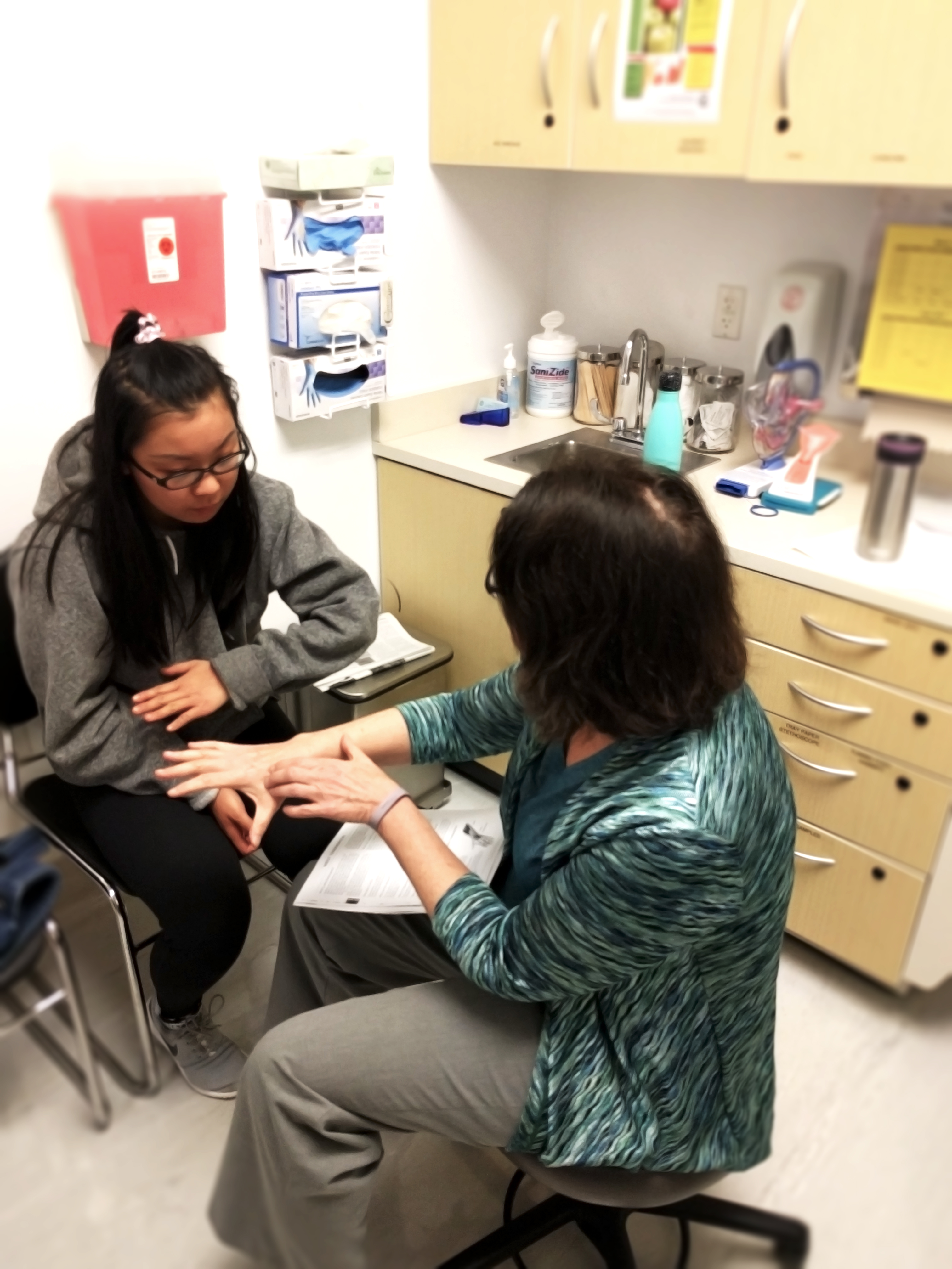 Nurse practitioner Mary Redfern is showing City College Student Brenda Chu how to deal with pain she’s feeling in her arm.  