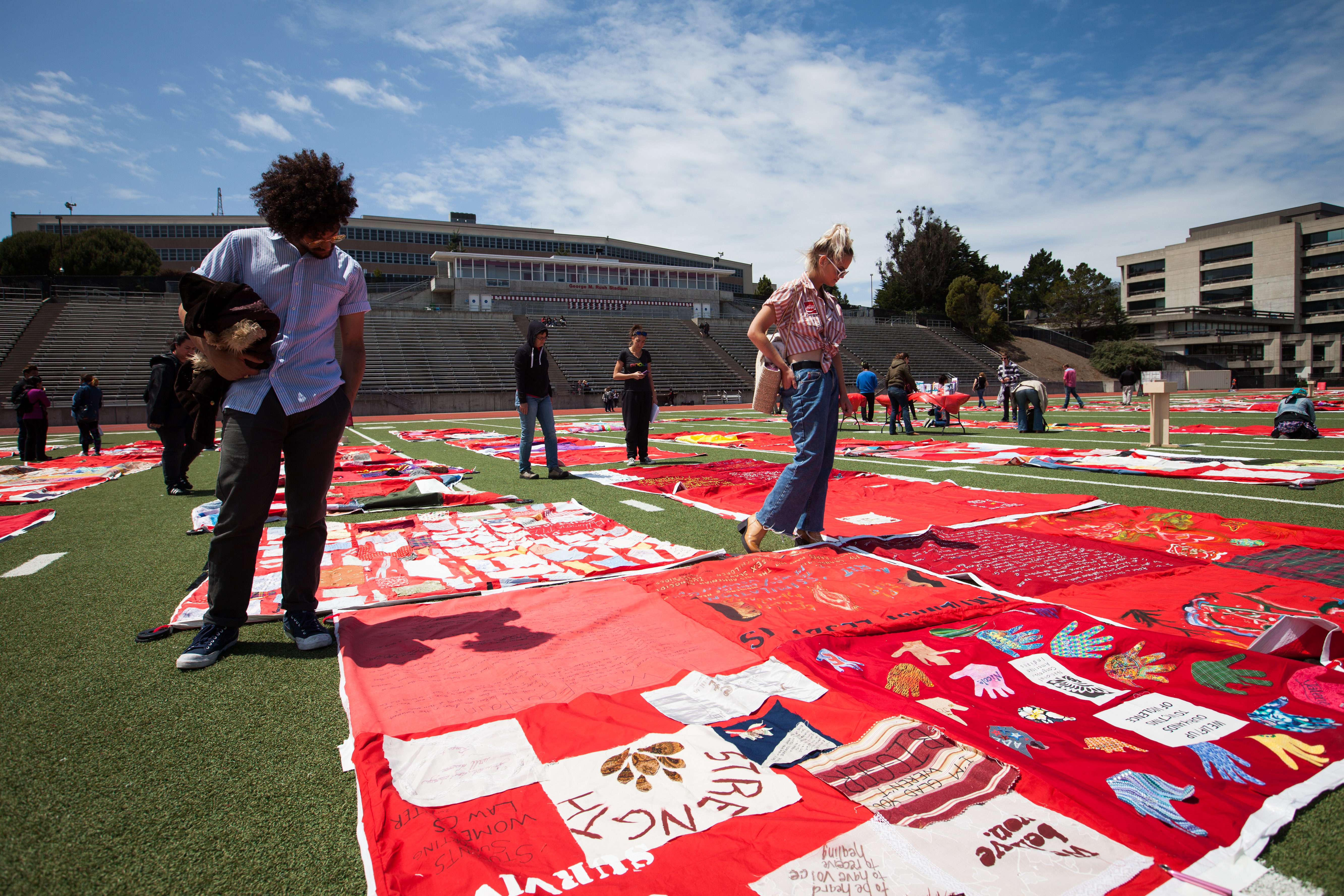 People view the exhibit of The Monument Quilt, an ongoing collection of stories from survivors of rape and abuse; the quilts are displayed on the football field of George M. Rush Stadium at City College of San Francisco Ocean Campus on Saturday, May 6, 2017. (Photo by Ekevara Kitpowsong)