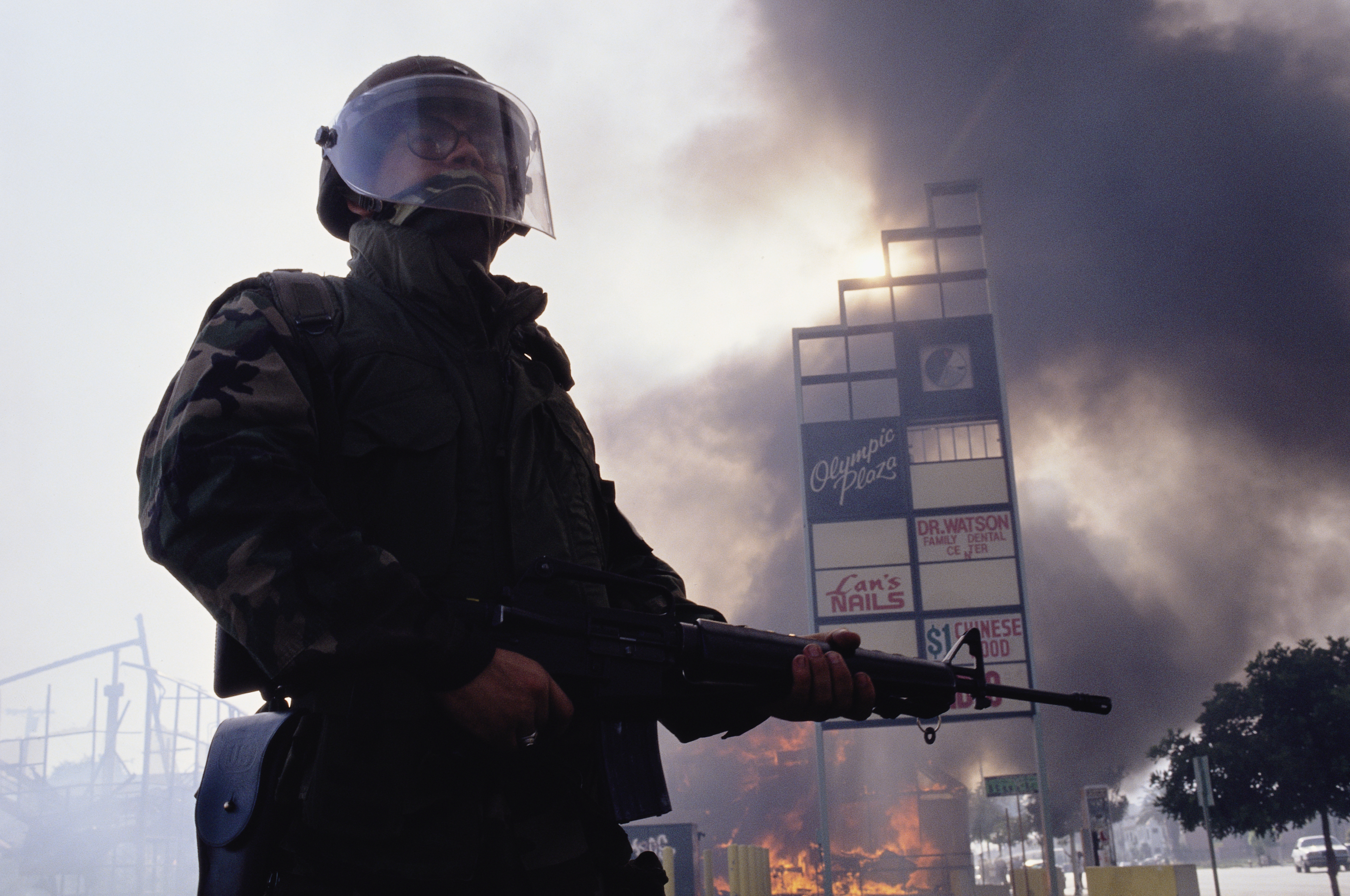 A member of the National Guard stands near burning building during the Los Angeles riots. In April of 1992, after a jury acquitted the police officers involved in the beating of Rodney King, riots broke out throughout South Central Los Angeles, killing 55 people, injuring another 2,000, and causing more than $1 billion in damage. (Photo by David Butow/Corbis via Getty Images)